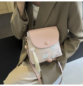 Détail d'un sac à bandoulière en cuir rose et tissu jacquard avec franges blanches