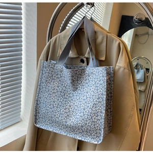 Detailed texture of light blue floral canvas tote bag with thick grey woven handle strap