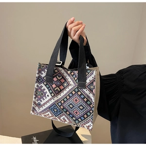 Detail of ethnic woven tote bag with colorful geometric patterns and black strap