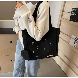 Détail du sac fourre-tout en toile noire avec broderie colorée et porte-monnaie assorti