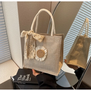 Détail du sac cabas tissé beige avec patch de marguerite et ruban en dentelle