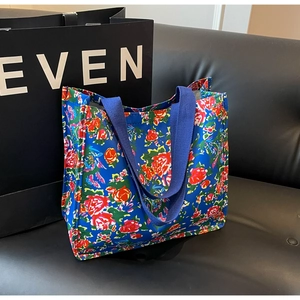 Détail du sac cabas en toile bleue avec des broderies florales rouges et jaunes vives