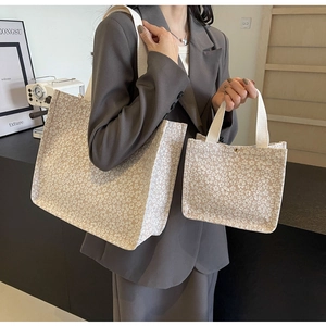 Détail d'un ensemble de sacs fourre-tout en toile à fleurs portés avec un costume décontracté