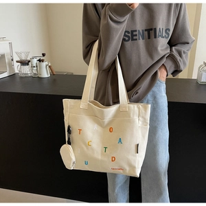 Détail du sac cabas en toile avec lettres colorées et petit porte-monnaie rond