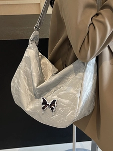 Sac hobo plissé argenté métallisé avec détail papillon porté par un mannequin
