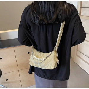 Detail of light green pleated crossbody bag with pearl and silver chain shoulder straps