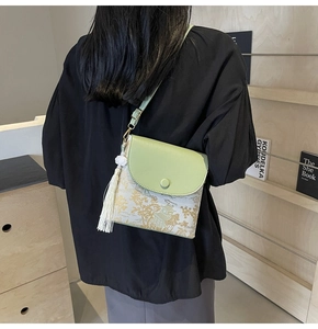 Détail d'un sac bandoulière blanc avec imprimé doré et rabat en cuir vert élégant