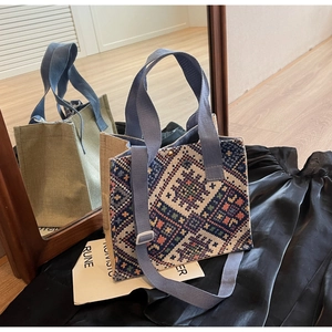 Detail of ethnic geometric woven tote bag showing blue webbed handle and side texture