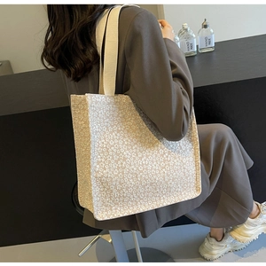 Détail du sac cabas blanc avec broderie florale dense et large bandoulière en tissu tissé