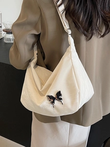 Sac hobo blanc froncé avec charme papillon porté par un mannequin dans un intérieur