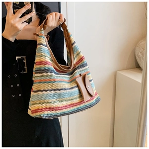 Detail of colorful striped woven tote with brown leather handles and small hanging pouch