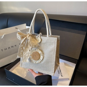 Détail du sac en jute avec patch tournesol tricoté et nœud en dentelle sur boîte