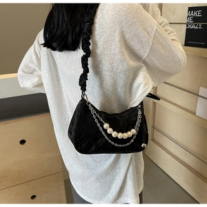 Detail of black pleated crescent bag featuring cloud strap, silver chain and white pearls