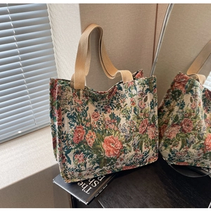 Detail of vintage floral jacquard tote bag with dual canvas handles on a book