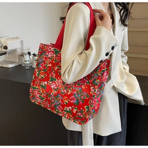 Détail du motif floral coloré sur un grand sac cabas en toile rouge avec une bandoulière large