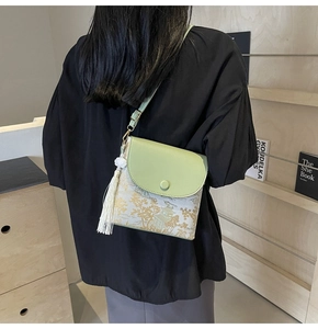 Vue détaillée du rabat en cuir vert et du tissu floral d'un sac bandoulière avec pompon
