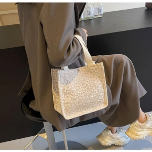 Detail of floral texture on canvas tote bag held by model in soft natural lighting