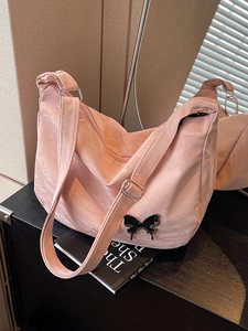 Sac à bandoulière plissé rose avec boucle papillon dans un décor chaleureux