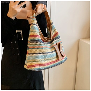 Detail of colorful striped woven tote bag with brown PU handles and a mini pouch charm