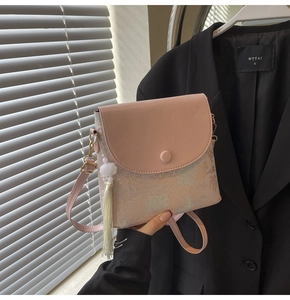Détail du sac seau rose brodé avec motif traditionnel et pendentif à pompon blanc