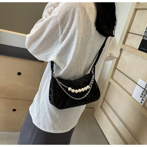 Detail of black pleated hobo bag with large pearl chain and shiny metallic chain accents
