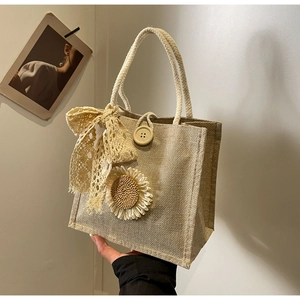 Détail d'un sac cabas tissé marron clair avec tournesol et nœud en dentelle