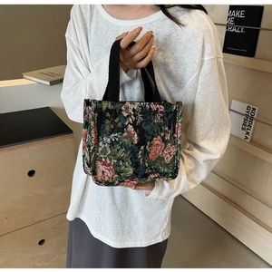 Detail of floral tapestry tote bag featuring vintage rose pattern and black canvas handles