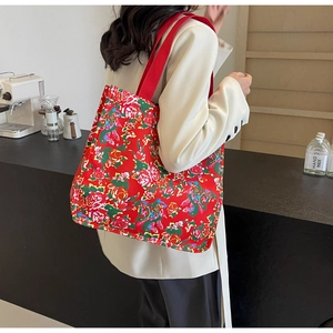 Détail d'un sac cabas en toile rouge avec imprimé floral traditionnel et large bandoulière