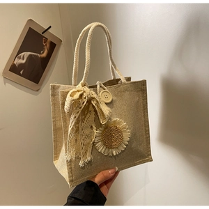 Détail du sac en toile de jute beige avec tournesol tricoté et nœud en dentelle