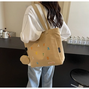 Détail du sac cabas en toile kaki avec broderies colorées et petit porte-monnaie rond assorti