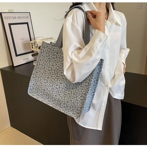 Detail of light blue floral canvas tote bag featuring white flower patterns and wide straps