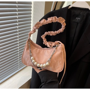 Detail of pink baguette bag with cloud ruffle strap, silver chains and pearl accents