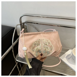 Détail du sac rose avec broderie florale, pompon en soie et ornement en pierre de jade