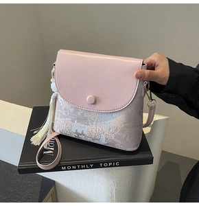 Détail du sac seau rose avec imprimé artistique de paysage et pompon blanc décoratif