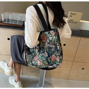 Detail of large floral canvas tote bag showing vintage embroidery and black straps
