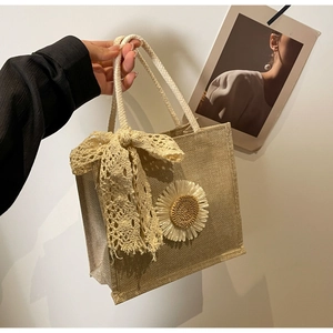 Détail du sac cabas en paille tissée avec nœud en dentelle, marguerite et anse coton