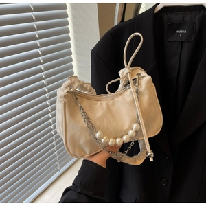 Detail of off-white ruched underarm bag featuring decorative large pearl chain