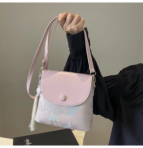 Détail du sac seau rose avec motifs artistiques peints à la main et gland décoratif