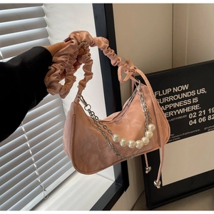 Close-up of pink satin shoulder bag with pearl chain and ruched handle texture