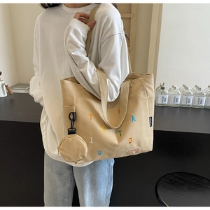 Détail du cabas en toile beige avec broderie colorée et petit porte-monnaie assorti