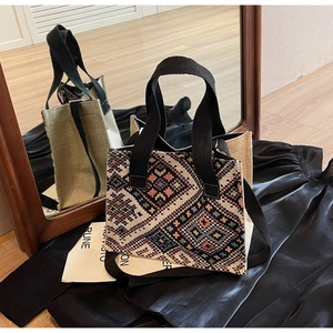 Macro detail of geometric ethnic woven patterns and black fabric handles on crossbody bag