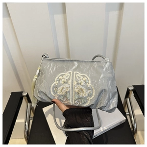 Gros plan du sac à bandoulière gris argenté avec broderie florale et détails de glands