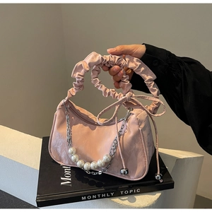 Detailed macro view of pink crescent bag with pearl chain and ruched handle
