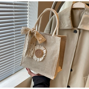 Détail d'un sac en lin orné d'une marguerite blanche et d'un nœud en dentelle délicate
