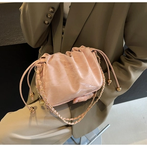 Pink pleated drawstring cloud bag with gold metal chain strap held by model