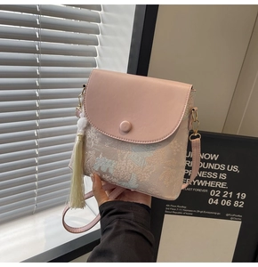 Détail du sac bandoulière rose clair en tissu jacquard avec long gland blanc