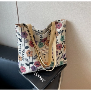 Close-up of vintage floral canvas tote bag featuring colorful flower patterns and textile labels