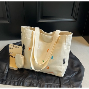 Détail du cabas en toile blanc cassé avec broderie arc-en-ciel et mini porte-monnaie