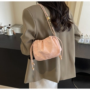 Detail of pink pleated PU leather shoulder bag with gold chain strap and metal bead decoration