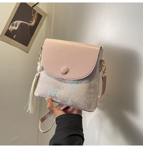 Détail du sac seau en cuir rose avec motif de paysage et accessoire de gland en soie